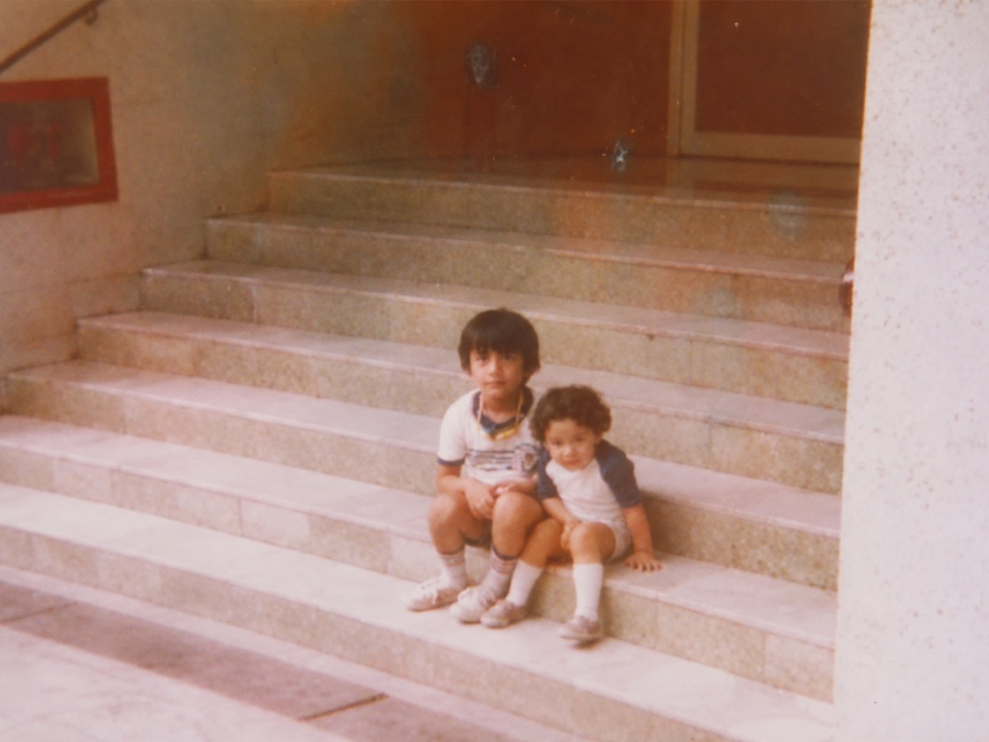 Ahmer Kalam and his brother sitting on steps as children
