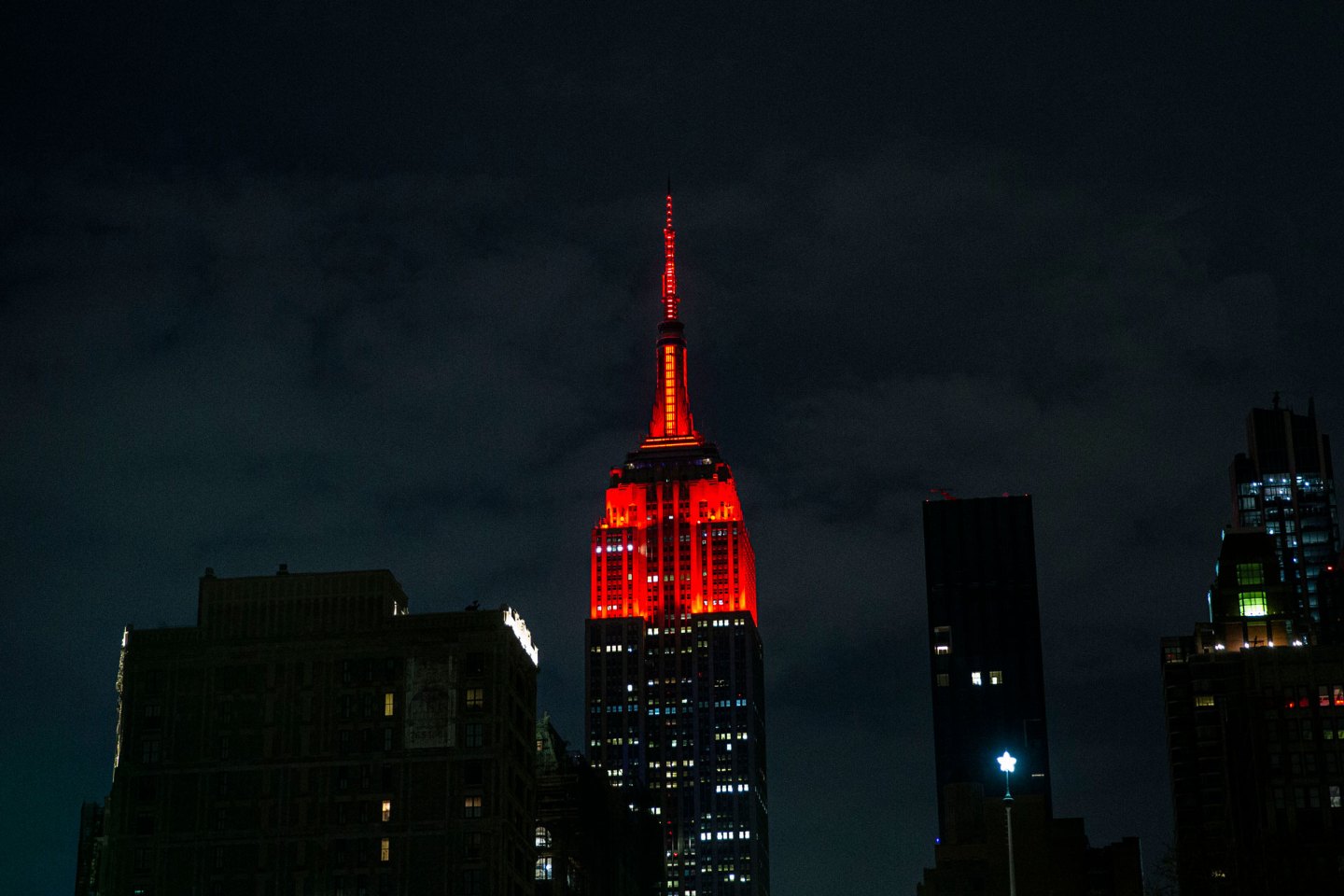 The Empire State Building lit red at night — photograph by Ahmer Kalam